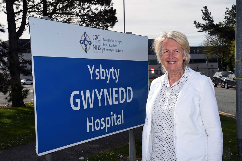 Sian Gwenllian yn sefyll o flaen arwydd Ysbyty Gwynedd